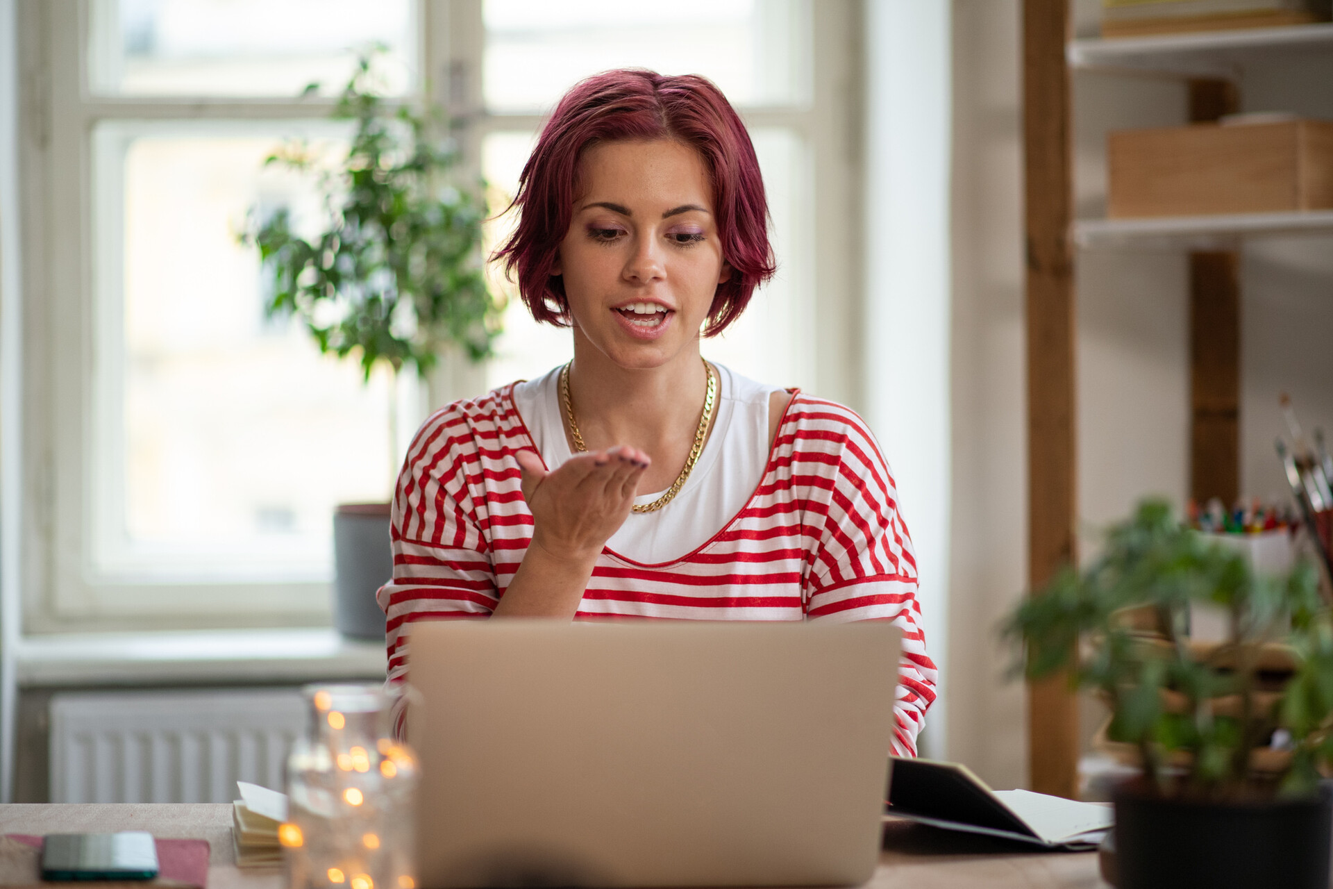 Frau mit rosa Haar benutzt Zeichensprache, während sie am Laptop sitzt