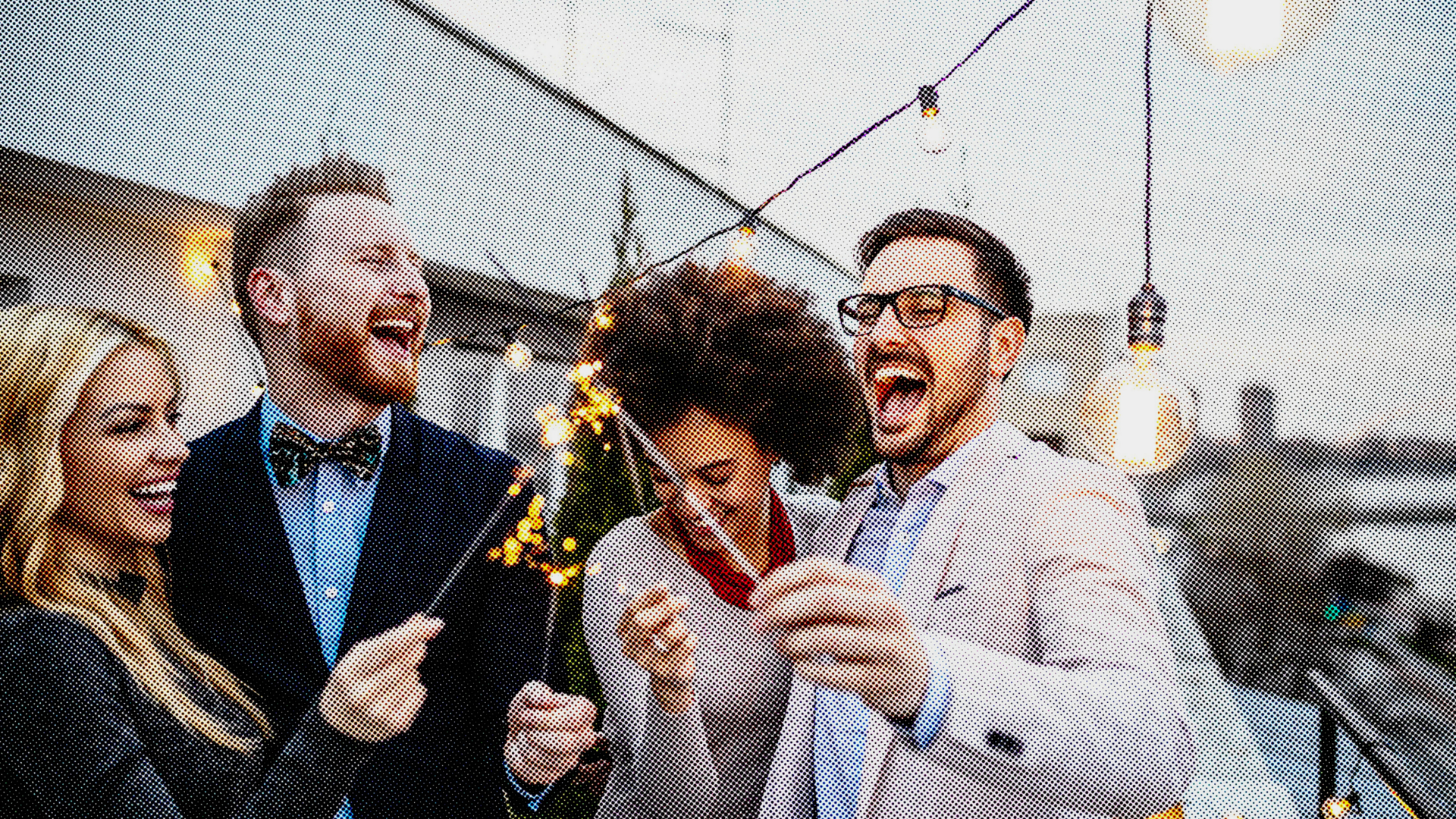 Vier Freunde, zwei Männer und zwei Frauen, stehen draußen und feiern mit Wunderkerzen Weihnachten