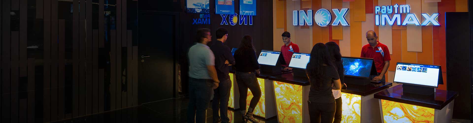 INOX Leisure-Kunden stehen in der Warteschlange und werden von Mitarbeitern bedient