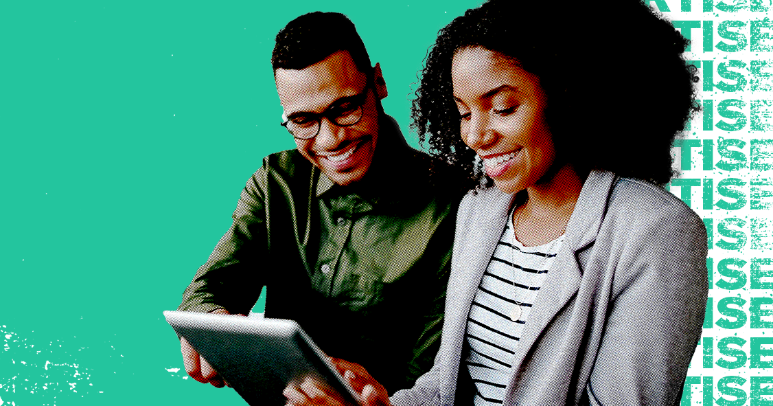 Two people smiling and working on an ipad