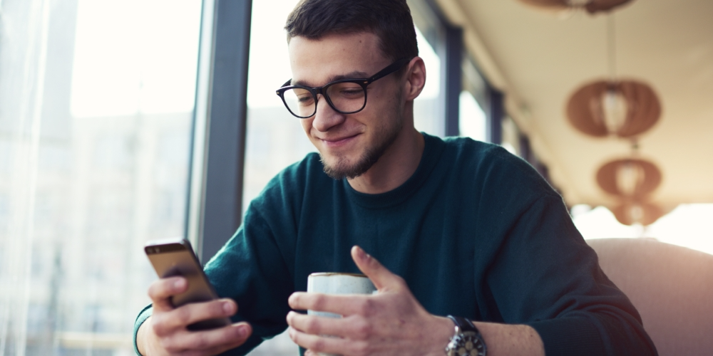 Young owner of coffee shop drinking cup of coffee